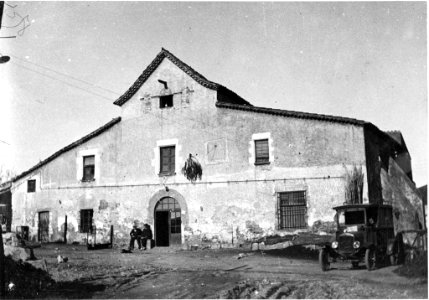 Façana de Can Solà amb gent i un cotxe d'època