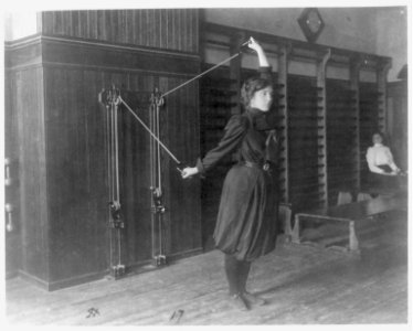 Female student exercising with a wall-mounted device using ropes and pulleys, Western High School, Washington, D.C. LCCN2001699133
