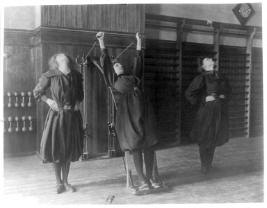 Female students exercising, one with a wall-mounted device using ropes and pulleys, Western High School, Washington, D.C. LCCN2001699134