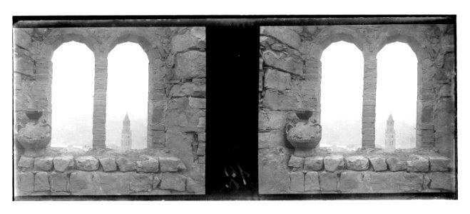 Finestra geminada d’una antiga construcció . Al fons, campanar de Sant Pere