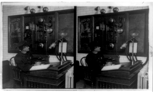 Fireman at desk in front of fire alarm LCCN96509032
