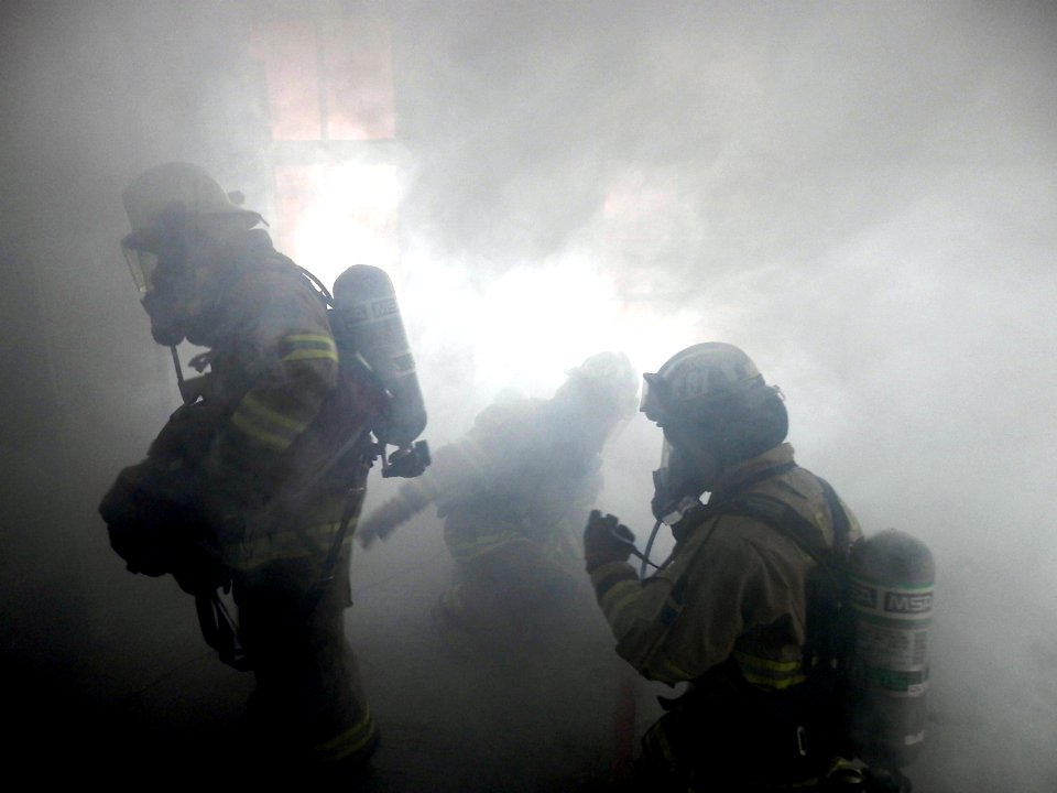 Firefighters navigate a smoke-filled room. (8696786470)