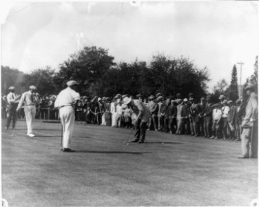 Golfer putting on green before large gallery LCCN2013646106