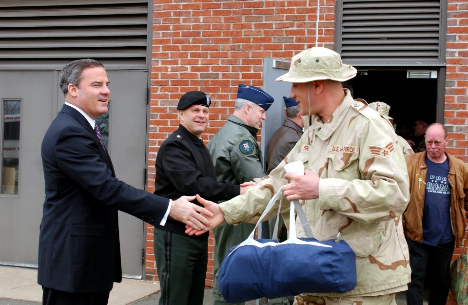 Governor John G. Rowland and Adjutant General William A. Cugno shake hands with Senior Airman Juan F. Perez