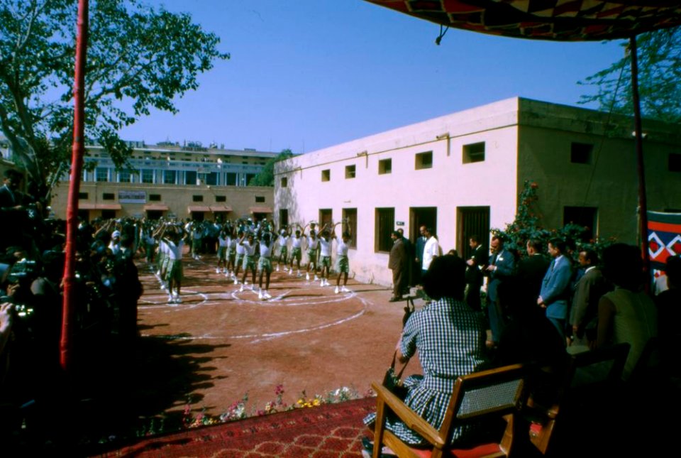 First Lady Jacqueline Kennedy watches a group of children perform a dance during her visit to Bal Sahyog