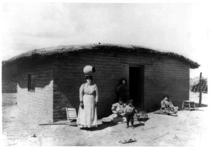 Five Pima Indians posed outside adobe house-one woman is standing with a piece of pottery on her head LCCN92513883