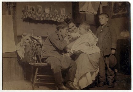 Flash light photo of John Sousa, his mother and some brothers and sisters. John is sitting. Crowded, dirty home. LOC cph.3b32766