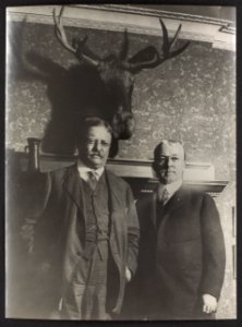 Flashlight taken of Col. Roosevelt and Professor Goode of the Chicago University, in front of a mounted moose head over Professor Goode's fireplace Roosevelt was then campaigning for the LCCN2009631492