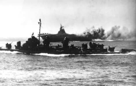 Fletcher-class destroyer passes by the burning USS Intrepid (CV-11) on 16 April 1945 (80-G-328441)