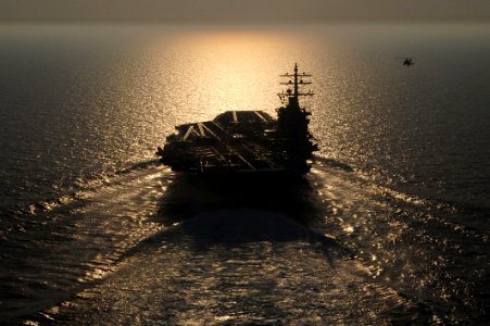 Flickr - Official U.S. Navy Imagery - A helicopter flies the national ensign alongside USS Dwight D. Eisenhower.