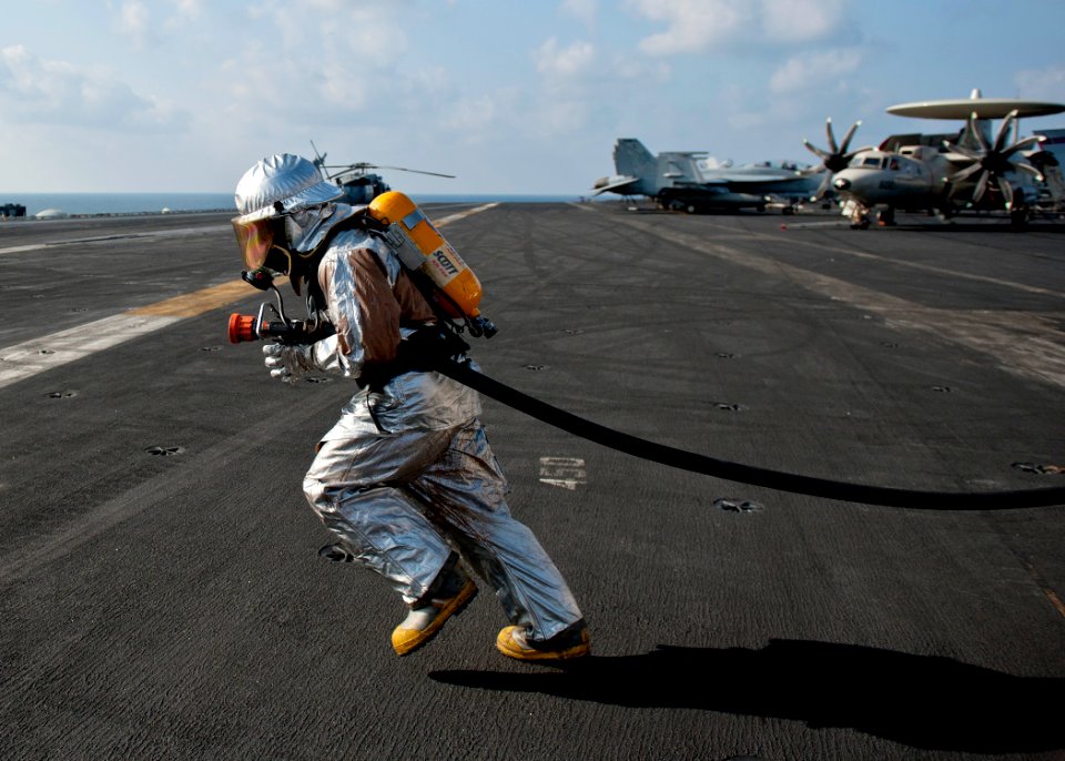 Flickr - Official U.S. Navy Imagery - A Sailor carries a fire hose during a flight deck fire drill.