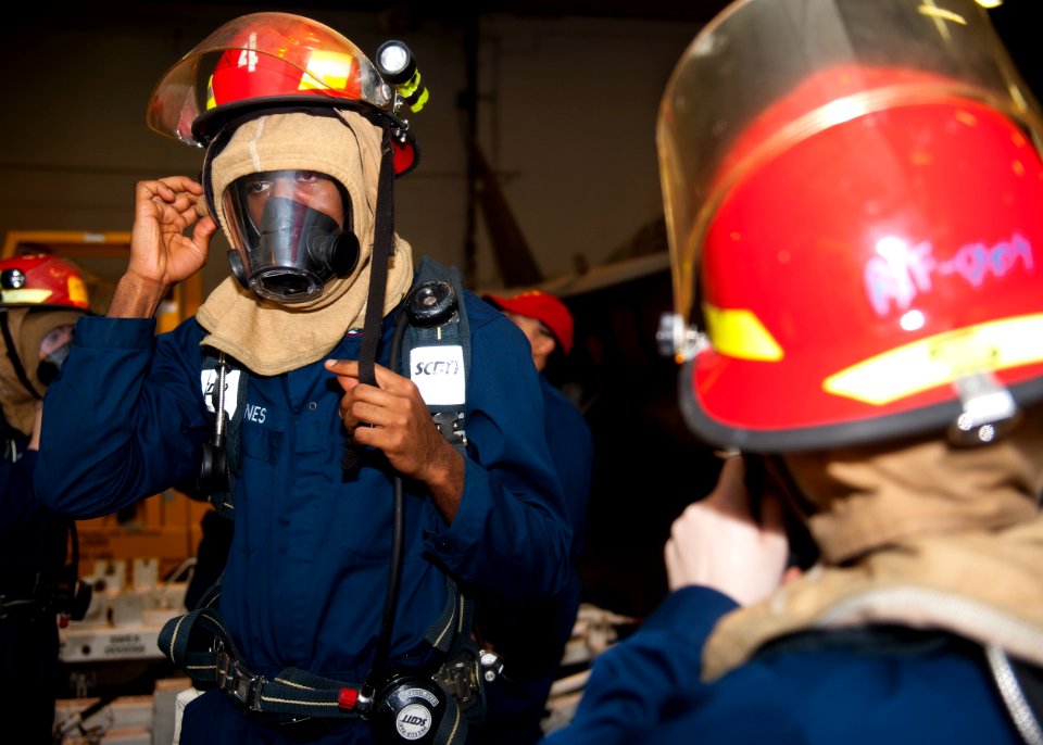 Flickr - Official U.S. Navy Imagery - A Sailor dons a firefighting helmet.