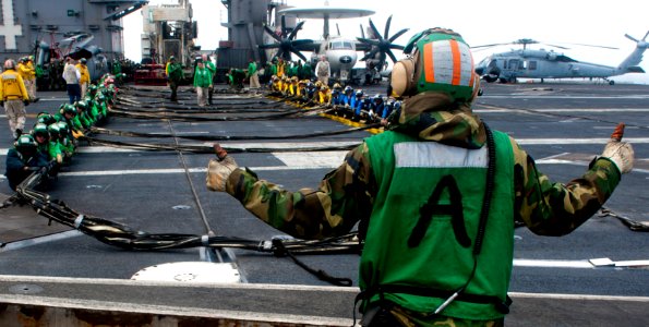 Flickr - Official U.S. Navy Imagery - A Sailor signals for Sailors to set up the barricade during flight deck drills.