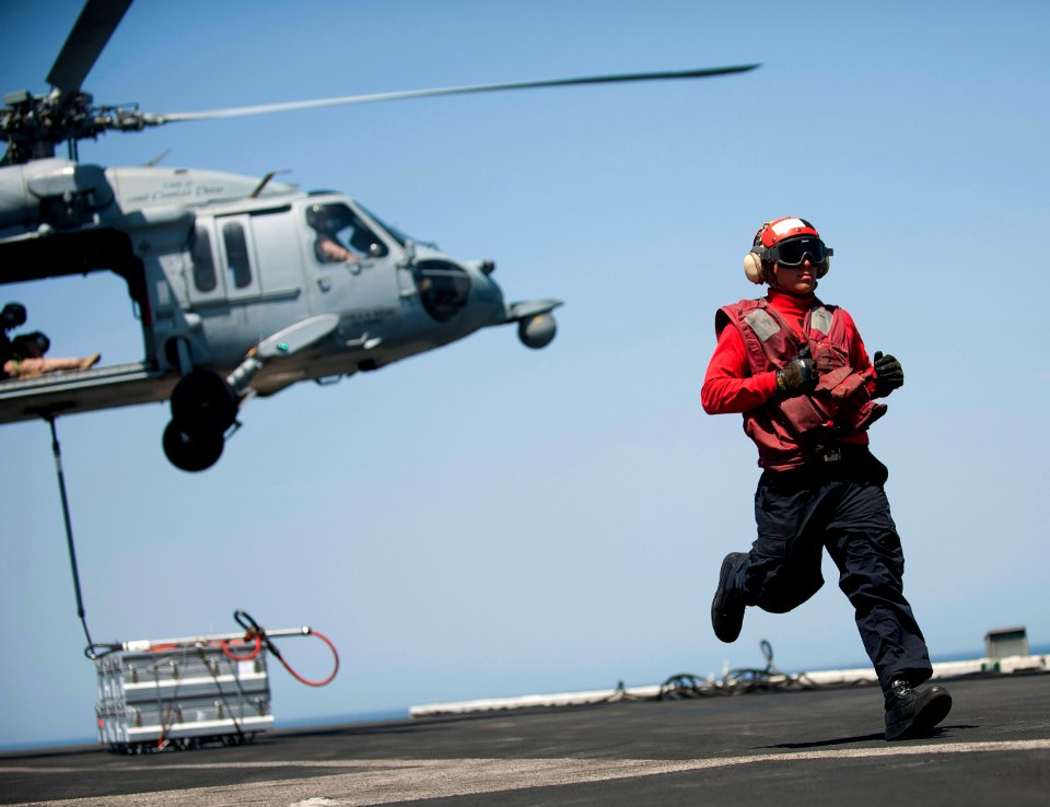 Flickr - Official U.S. Navy Imagery - A Sailor runs to clear the area after attaching crates of ordnance to a helicopter.
