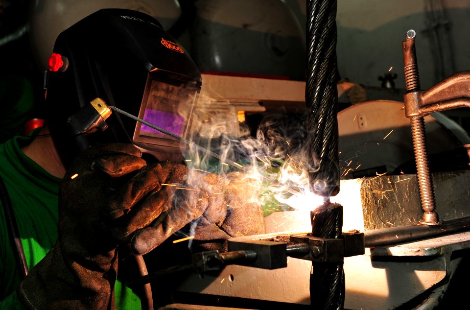 Flickr - Official U.S. Navy Imagery - Iowa native-Sailor welds two arresting gear cables together during a reweave