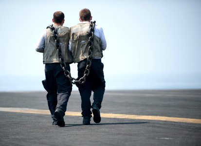 Flickr - Official U.S. Navy Imagery - Sailors carry a heavy chain used to secure aircraft for high power turns on the flight deck.
