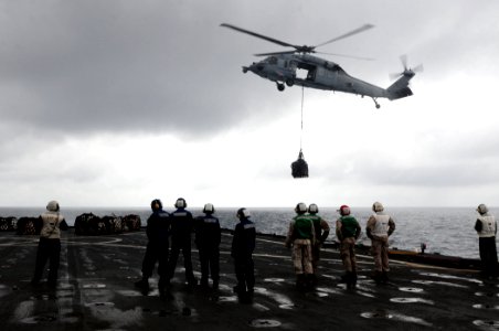 Flight deck personnel wait for an MH-60S Seahawk helicopter to deliver supplies aboard the dock landing ship USS Comstock (LSD 45) March 17, 2011, during operations in the Pacific Ocean 110317-N-RC734-251