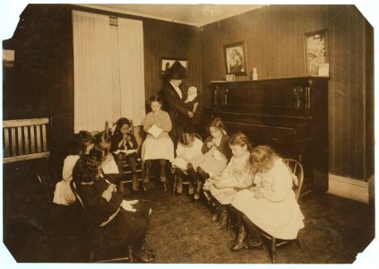 For Child Welfare Exhibit 1912-13.) Sewing class in Sprague House Settlement Providence, R.I. The Director is holding a newly-arrived deserted baby LOC cph.3b06722