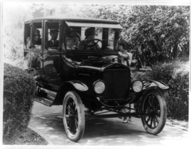 Ford 4-door sedan, front view, with four passengers and a woman driver, another woman standing beside automobile talking to the driver LCCN95500778