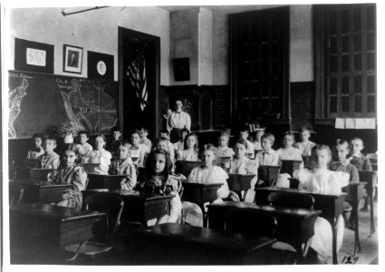 Grade school children posed in classroom, with teacher standing in back of room, Washington, D.C. LCCN96525653