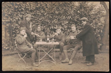 Four unidentified soldiers in uniform drinking wine as two civilians hand them papers, probably in France LCCN2018645959