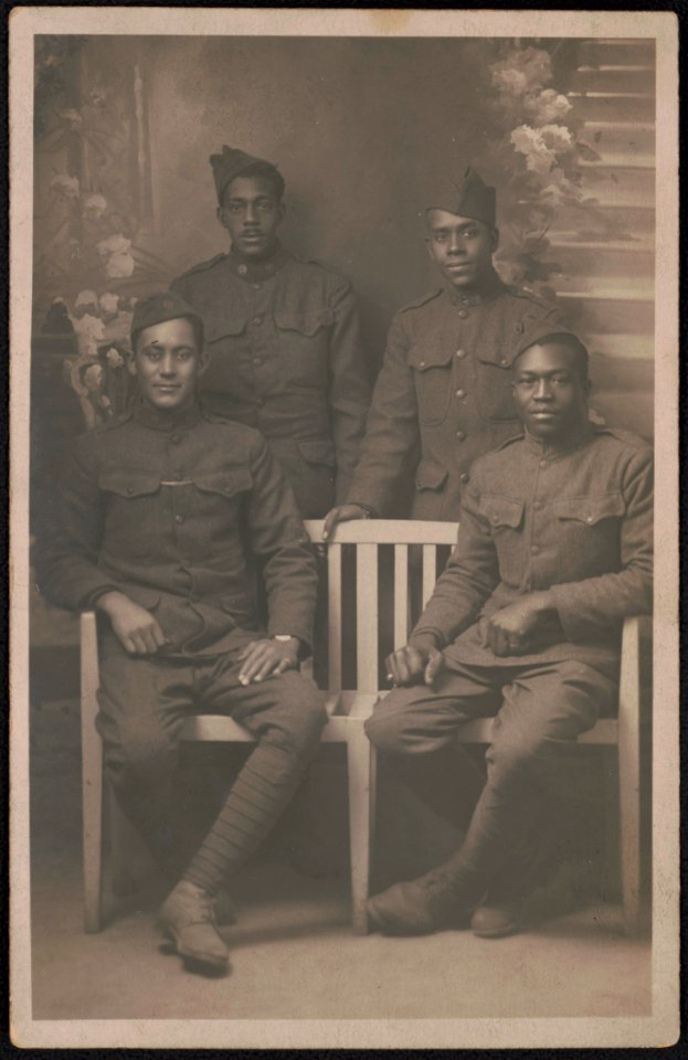 Four unidentified African American soldiers in uniforms and overseas caps in front of painted backdrop LCCN2017648684