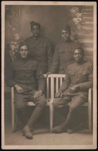 Four unidentified African American soldiers in uniforms and overseas caps in front of painted backdrop LCCN2017648684 photo