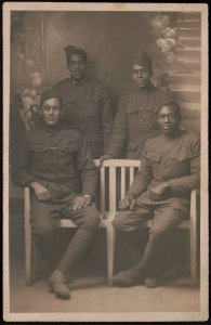 Four unidentified African American soldiers in uniforms and overseas caps in front of painted backdrop LCCN2017648684