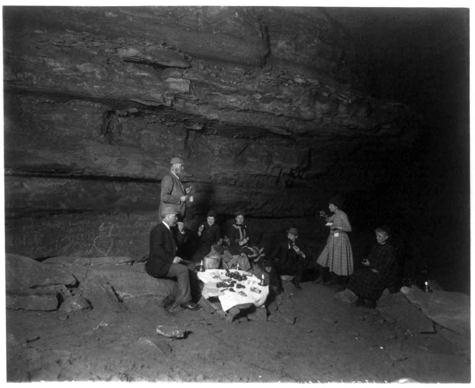 Frances Benj. Johnston with group of men and women having picnic lunch inside Mammoth Cave, Ky. LCCN2005686754