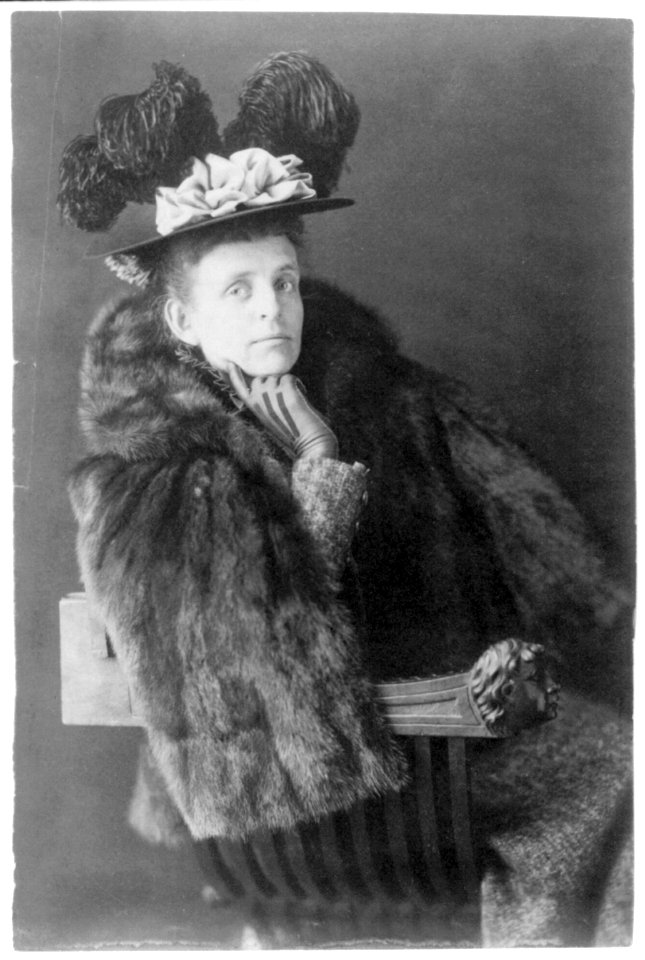 Frances Benjamin Johnston, 1864-1952, half length, seated, facing right, wearing fur jacket and plumed hat LCCN2006689793