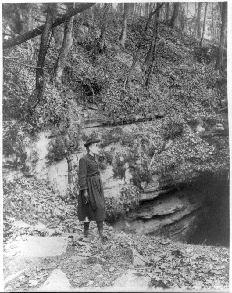 Frances Benjamin Johnston, full, standing by wooded cliff at entrance to Mammoth Cave LCCN2006688466