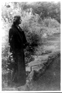 Frances Benjamin Johnston, full-length portrait, standing in garden, right profile LCCN96510208
