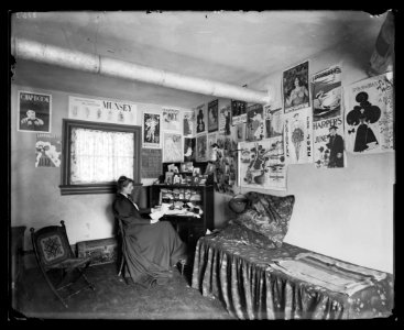 Frances Benjamin Johnston seated at a desk in her studio-office, with adverstising posters on the walls, including the Chap Book, Harper's, and Lippincott's magazines LCCN2017645690 photo