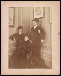Frances Benjamin Johnston, full lgth., standing, in costume, wearing mustache, posed with 2 other people LCCN2002710481