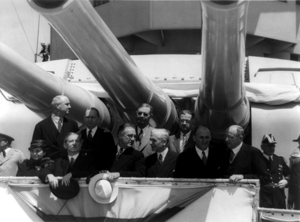 Franklin D. Roosevelt and others posed under large guns on battleship