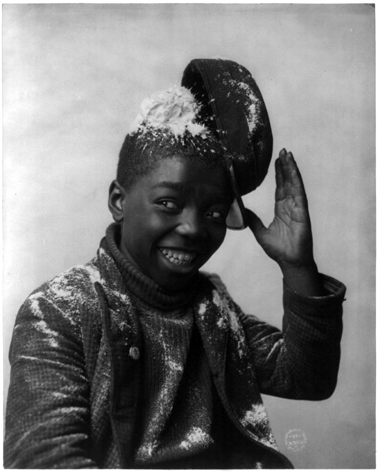 Grinning African American boy with hat knocked askew by snowball LCCN2003675171
