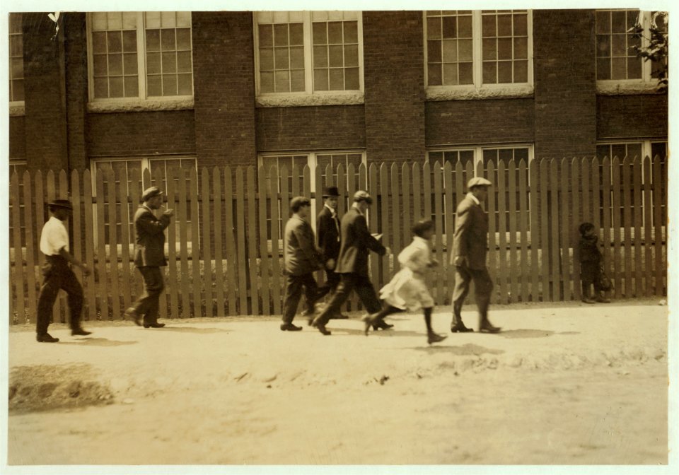 Group going out at noon from the Kilburn Mills. Little girl running is one of the workers. LOC nclc.02230