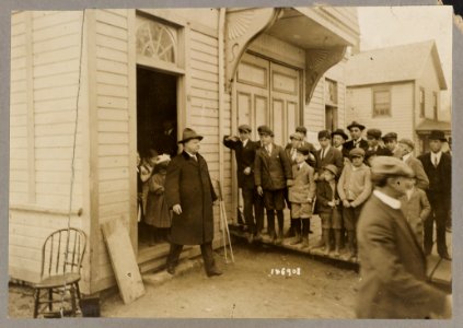 Group of children watching Theodore Roosevelt as he exits a building LCCN2013651225