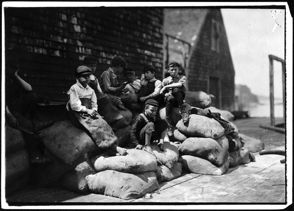 Group of young cutters in a canning factory, waiting for more fish. They all work, but they waste a good deal of time... - NARA - 523453