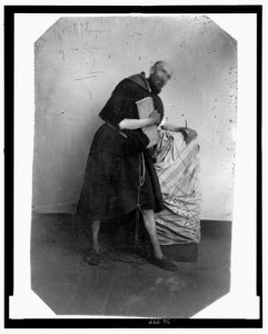 Full-length portrait of a man dressed as a monk, leaning on a cloth-covered crate LCCN2006689589