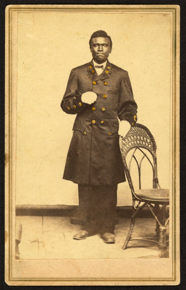 Full-length portrait of an African American man wearing long coat and gloves, standing, facing front LCCN2010647823