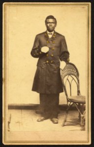 Full-length portrait of an African American man wearing long coat and gloves, standing, facing front LCCN2010647823