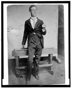 Full-length portrait of a man standing in front of a wooden bench LCCN2006689583