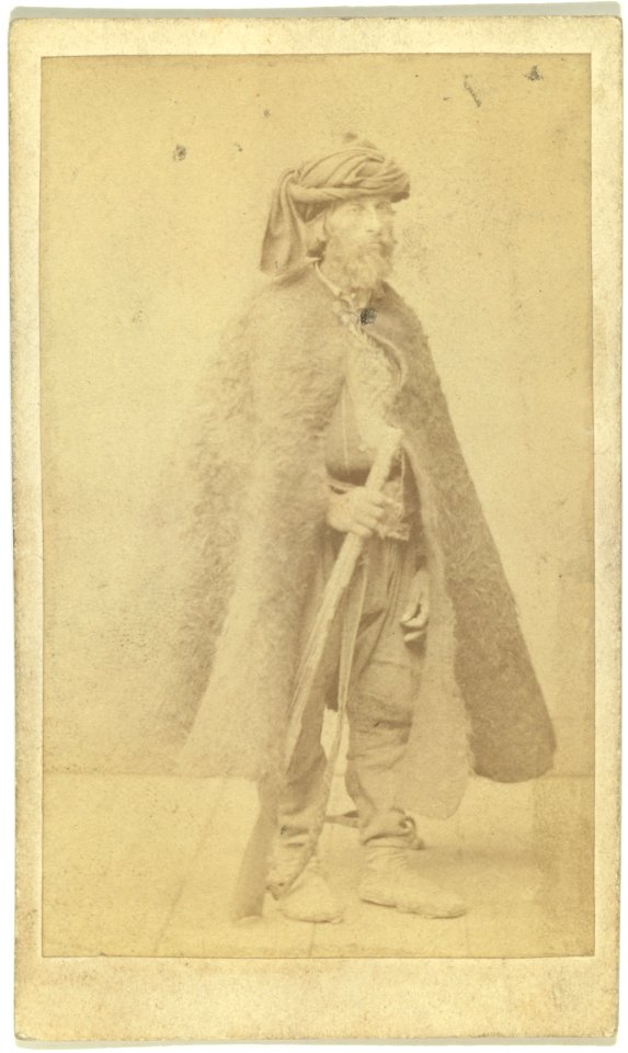 Full-length portrait of man wearing cloak and holding rifle LCCN99615607