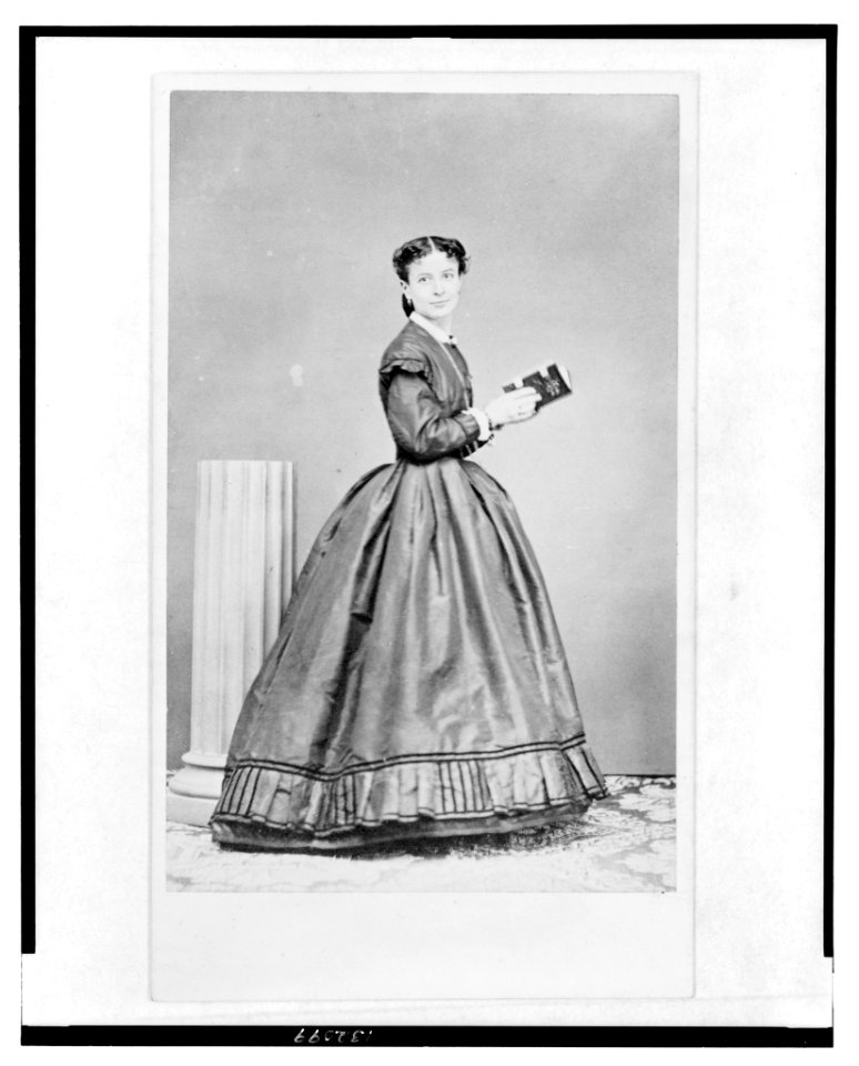 Full-length portrait of a woman, standing, turned right, facing front, holding a book LCCN2005692480