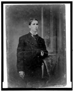 Full-length portrait of a young man, standing with one hand in suit jacket LCCN2006689592
