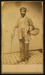 Full-length portrait of an African American man with a basket and a cane, standing, facing front LCCN2010647824