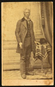 Full-length portrait of unidentified African American man in suit, standing next to a table) - Whiddit & Coffin, Photographers, 82 Water Street, Newburgh, N.Y LCCN2010647815