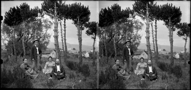 Grup de persones en un bosc i al fons la masia de Can Muntaner