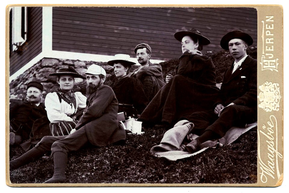 Gruppbild utanför Sylstugan vid invigningen 1897. Män och kvinnor sittande i slänt utanför raststuga - Nordiska Museet - NMA.0000050